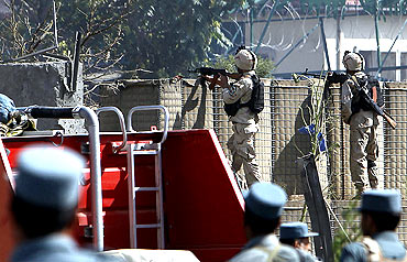Afghan commando troops and policemen take up position at the site the suicide attack in Kabul