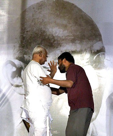 Anna Hazare (L) is helped by one of his supporters on the eighth day of his fast at Ramlila grounds in New Delhi