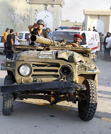 Libyan rebels ride a vehicle at Bab Al-Aziziya compound in Tripoli