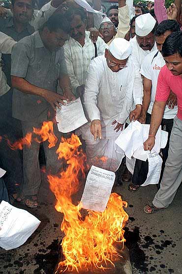 Anna Hazare and his supporters burn copies of the government version of Lokpal Bill