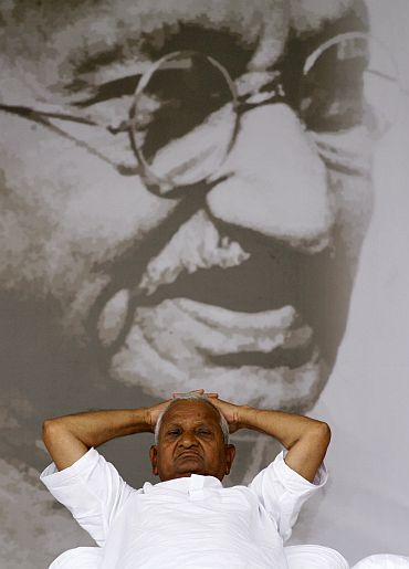 Anna Hazare rests in front of a portrait of Mahatma Gandhi
