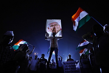 A Hazare supporter holds his portrait on the ninth day of Hazare's fast at Ramlila grounds in New Delhi