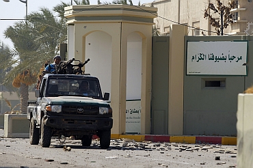 A rebel fighter is seen at the south gate of the Bab al Aziziya compound as they make a final push to flush out pro-Gaddafi forces from the compound in Tripoli. The sign on the wall reads Welcome, our dear guest