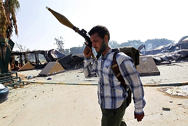A rebel fighter is seen at the south gate of the Bab al Aziziya compound