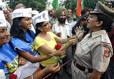 Supporters of Anna Hazare offer roses to a policewoman