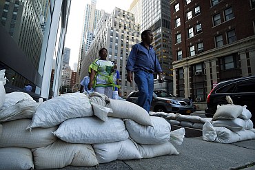 Pedestrians pass sandbags used to control possible floods at downtown Manhattan in New York