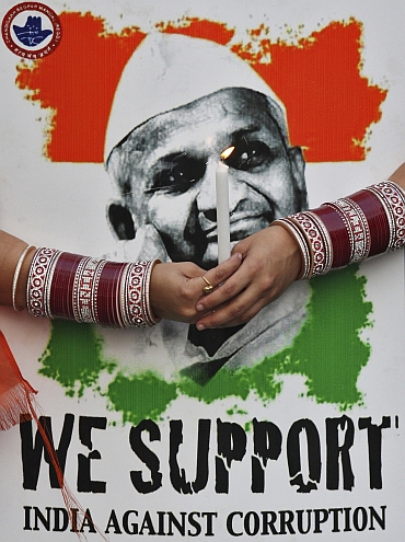 A supporter of Hazare holds a candle and his portrait during a candlelight protest against corruption in Chandigarh