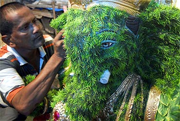 An artisan prepares a Ganesh idol out of blades of grass