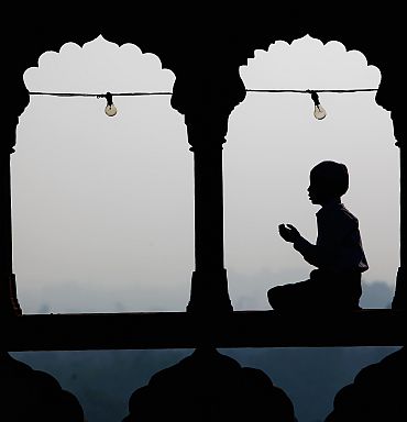 A Muslim boy prays as others gather during morning prayers at the Jama Masjid