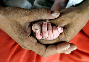A woman holds the hand of her newborn child in Akhera village in Haryana