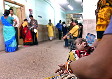 A woman holds a newborn waiting for a routine check-up at a hospital in Kolkata