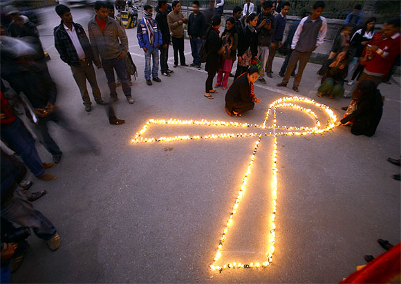 People gather around lit candles to mark the upcoming World AIDS Day in Kathmandu