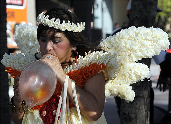 A member of the Population and Community Development Association, wearing a costume made of condoms, blows a condom during a march marking World AIDS Day in Pattaya