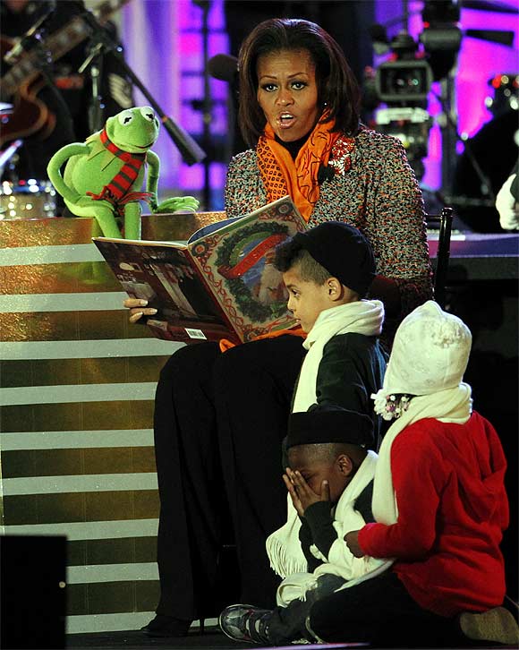 U.S. first lady Michelle Obama reads a Christmas story to children with the help of Kermit the Frog character, during the National Christmas Tree lighting ceremony in Washington