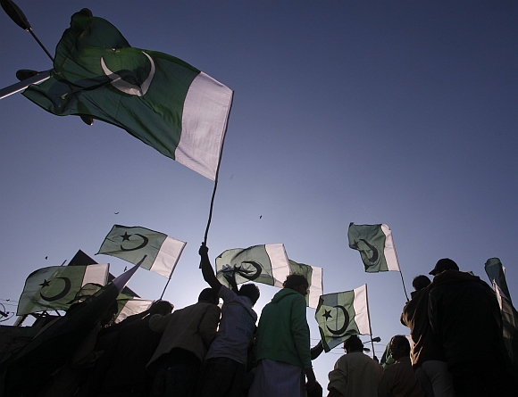 Traders wave Pakistan's national flag while taking part in a demonstration against NATO cross-border attack in Islamabad