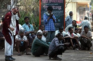 Daily wage workers wait for employment on a street side at an industrial area in Mumbai