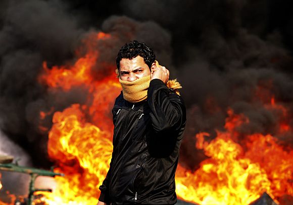 A protester stands in front of a burning barricade during a demonstration in Cairo January 28, 2011