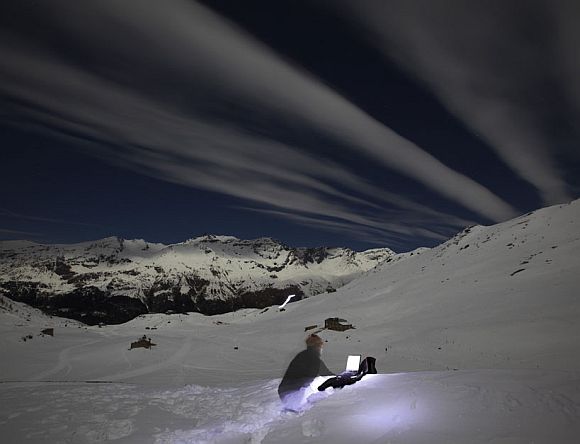 Switzerland's photographer Denis Balibouse files his pictures under a full moon sky from Mont-Cenis Pass Road in Lanslebourg during the Grande Odyssee sled dogs race January 19, 2011. This picture was taken with a long exposure