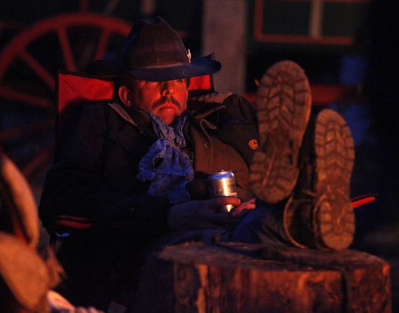 Wrangler Dale Wetz rests by the campfire after the group had gathered approximately 350 horses during Montana Horses' spring drive outside Three Forks, Montana April 22, 2011