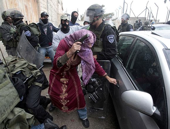 An undercover Israeli policeman dressed as a Palestinian woman opens a car door after detaining a Palestinian protester during clashes in Shuafat refugee camp, in the West Bank near Jerusalem May 15, 2011