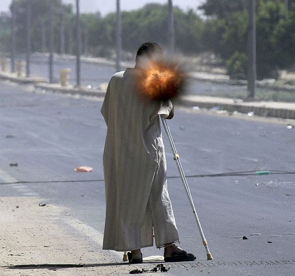 A rebel on crutches fires a rocket propelled grenade while fighting on the front line in Sirte September 24, 2011