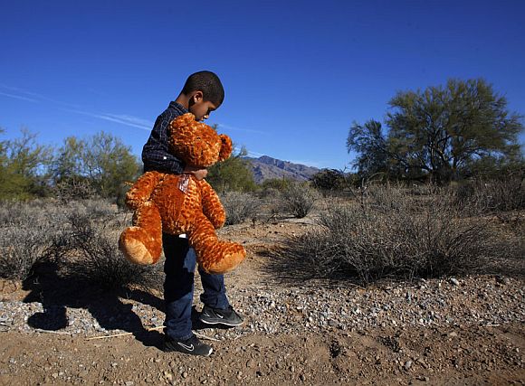 Nine-year-old Dante Mitchell, classmate of nine-year-old Christina Green, holds a stuffed bear he brought to her funeral in Tucson, Arizona January 13, 2011. Green was killed in the January 8 shooting that left six dead and wounded US Representative Gabrielle Giffords