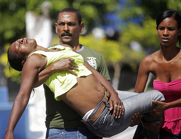 Relatives of one of the victims of a shooting at Tasso da Silveira school carry a family member who had fainted while attending the funeral at Realengo cemetery in Rio de Janeiro April 8, 2011