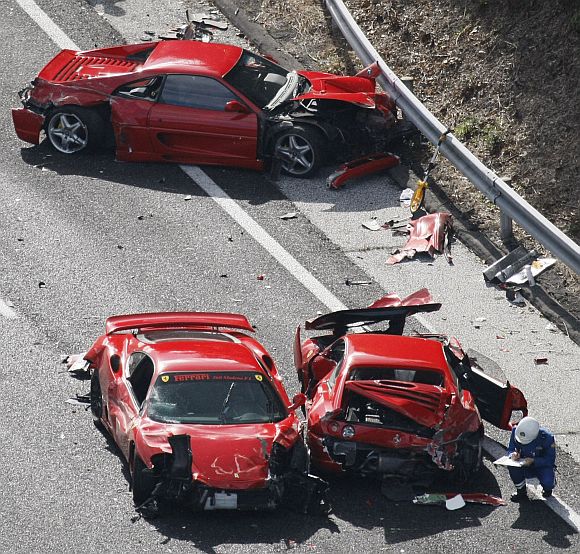 Police officers investigate wrecked luxury cars at the site of a traffic accident on the Chugoku Expressway in Shimonoseki, southwestern Japan