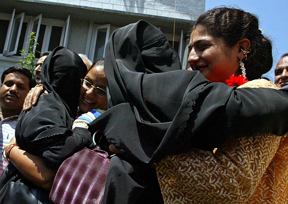 Migrant Kashmiri Hindu women hug veiled Kashmiri Muslim activists from the All Parties Hurriyat Conference before their meeting in Srinagar