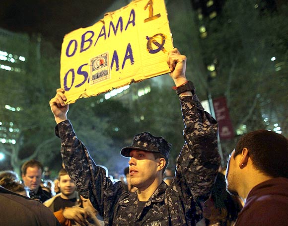 A man holds up a scoreboard displaying Obama - one, Osama - nil,  as thousands of people celebrate in the streets at Ground Zero, the site of the World Trade Centre, waving American flags and honking horns to celebrate the death of Al Qaeda founder and leader Osama bin Laden on May 1