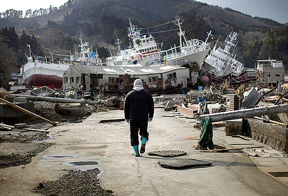 A man walks next to port area destroyed by the earthquake and tsunami in Kessenuma town, in Miyagi prefecture March 28