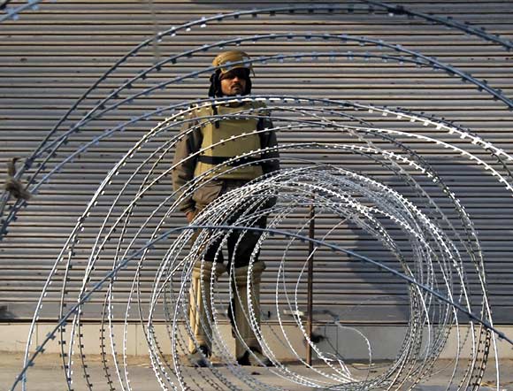 A policeman stands guard behind a barricade in Srinagar