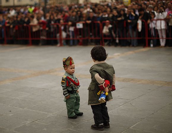 A child dressed up as a Spanish legionnaire looks at another holding a toy during the Holy Week in Malaga, southern Spain