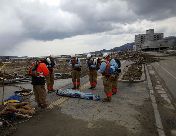 Rescue workers pay their final respects to a dead body retrieved from the rubble in Rikuzentakat, Iwate Prefecture, days after the area was devastated by an earthquake and tsunami March 17, 2011