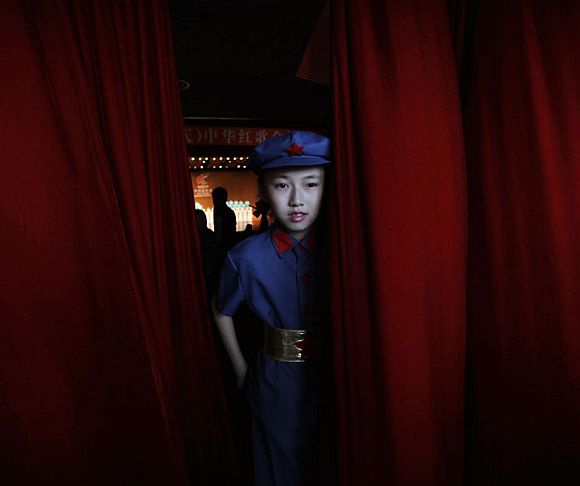 A schoolgirl participant, dressed as a Chinese Red Army soldier, walks through a red curtain during a revolutionary song singing competition to celebrate the upcoming 90th anniversary of the founding of the Communist Party of China (CPC), in Chongqing municipality June 30, 2011