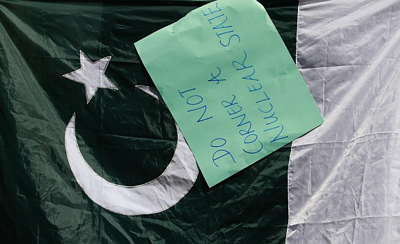 A placard hangs on a Pakistan flag during a protest against the US