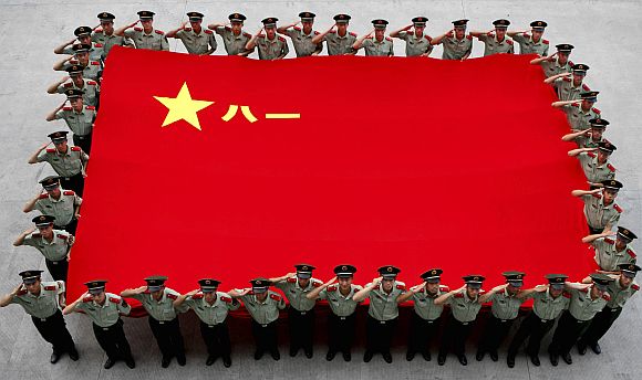 Paramilitary policemen salute as they hold a Chinese PLA flag to celebrate the anniversary of the founding of the PLA in Hangzhou, China