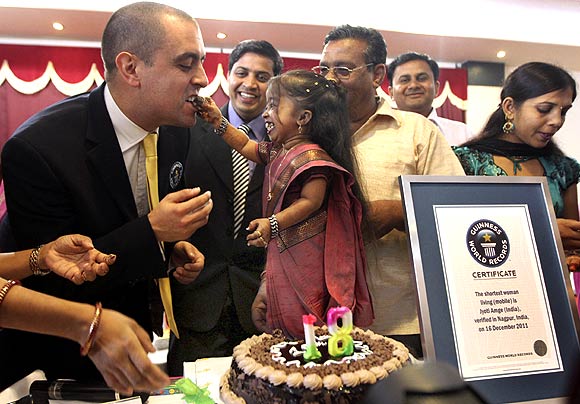 Jyoti Amge (C), the world's shortest living woman, offers a piece of cake to the Guinness World Records adjudicator Rob Molloy on her 18th birthday in Nagpur
