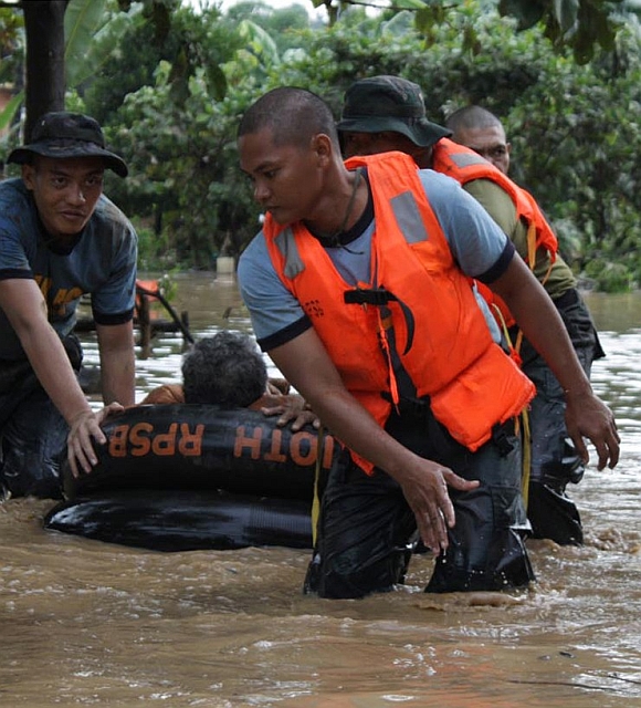 Philippine National Police rescuers use a rubber boat to evacuate a resident after flash floods brought by Typhoon Washi