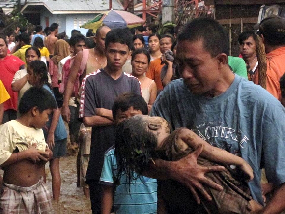 A father cries as he carries the body of his child, who was among hundreds killed by Typhoon Washi