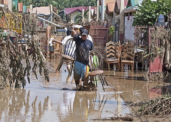 A resident carries items he salvaged from his damaged shanty after the flash floods hit Iligan city, southern Philippines
