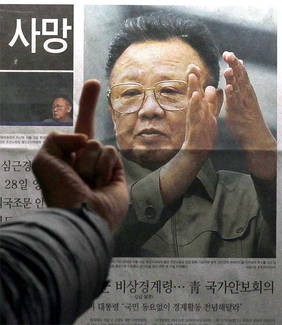 A man reacts at a picture of North Korean leader Kim Jong-il as he reads the reports of his death on the newspaper company's display board in Seoul