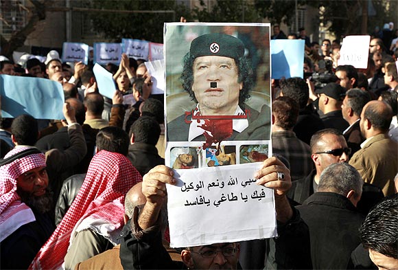 A protester holds up a poster of Libyan leader Muammar Gaddafi defaced as Adolf Hitler during a demonstration