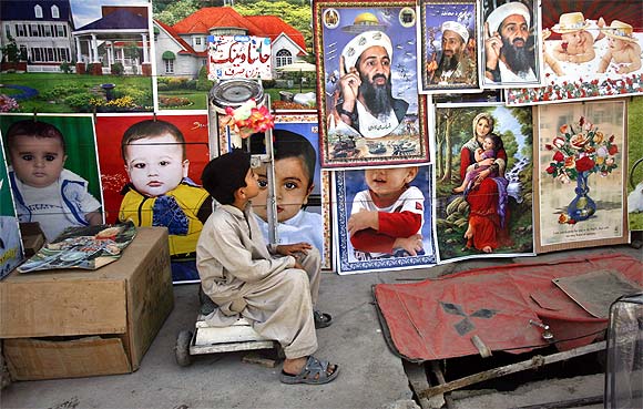 A child looks up at posters depicting slain Al Qaeda leader Osama bin Laden at a roadside stall in Quetta