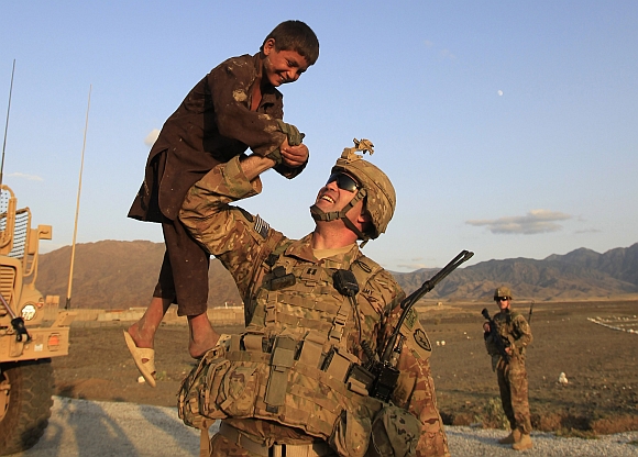 US military officer CPT Heiliger from Alpha Co, 2nd Battalion 35th Infantry, Task Force Cacti lifts a boy while on patrol in a village near Combat Outpost Penich in Khas Kunar district in Kunar