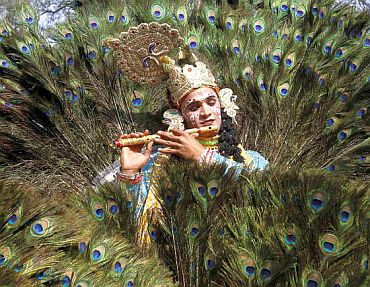 An artist dressed as Hindu Lord Krishna performs during the media preview
