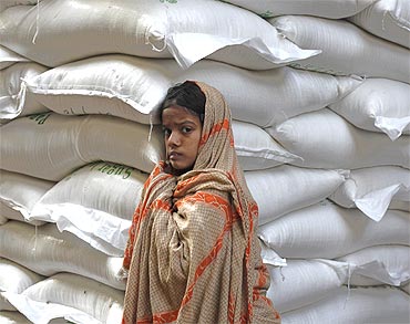 A Pakistani girl leans against sacks of sugar as she awaits handouts from customers at a wholesale market in Karachi