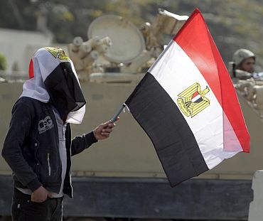 A supporter of Egyptian President Hosni Mubarak holds an Egyptian flag in front of an Egyptian army vehicle during a demonstration in Cairo