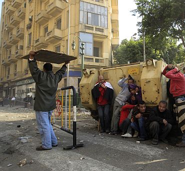 Demonstrators take cover during rioting between pro and anti Mubarak supporters