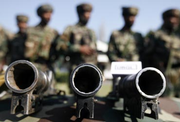 Army soldiers stand behind seized grenade launchers after a gunbattle with militants